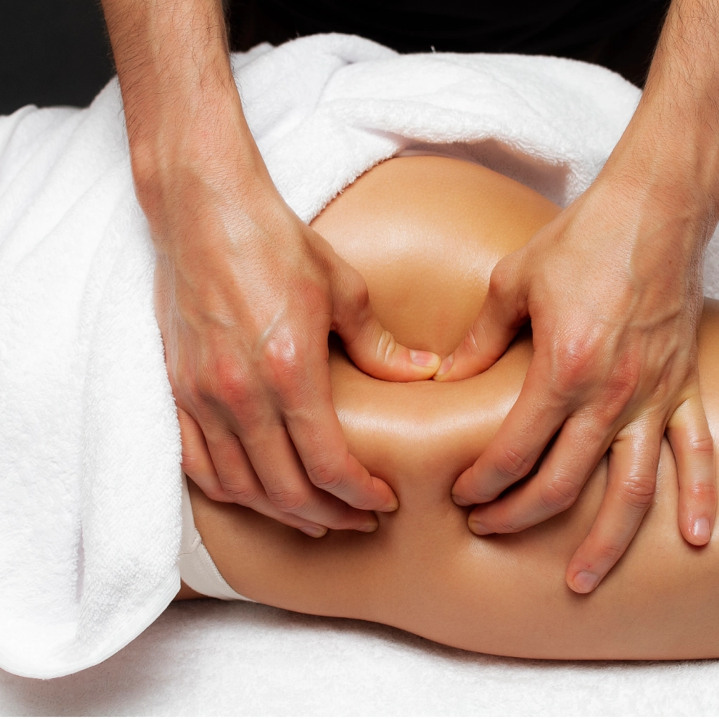 Manos realizando masaje de drenaje linfático para activar la circulación y reducir la retención de líquidos en tratamiento de fisioterapia estética.