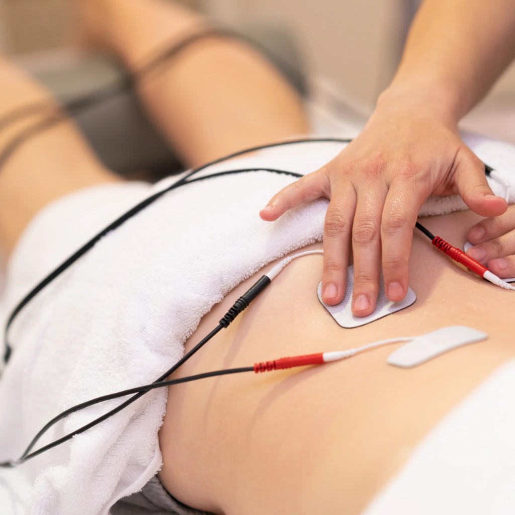 Aplicación de electroterapia en la zona lumbar durante una sesión de fisioterapia