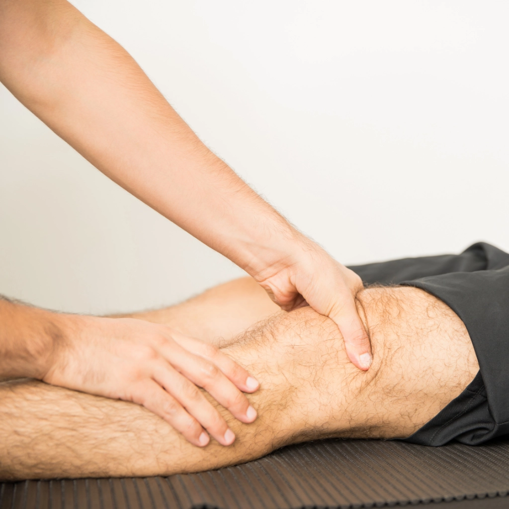 Fisioterapeuta aplicando presión para tratar una lesión de rodilla en deportista