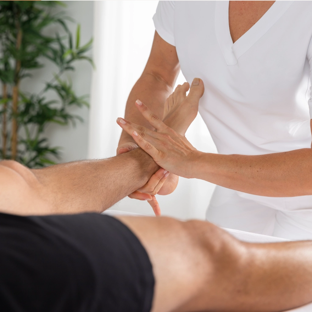 Fisioterapeuta aplicando masaje en pierna de deportista para aliviar sobrecarga muscular