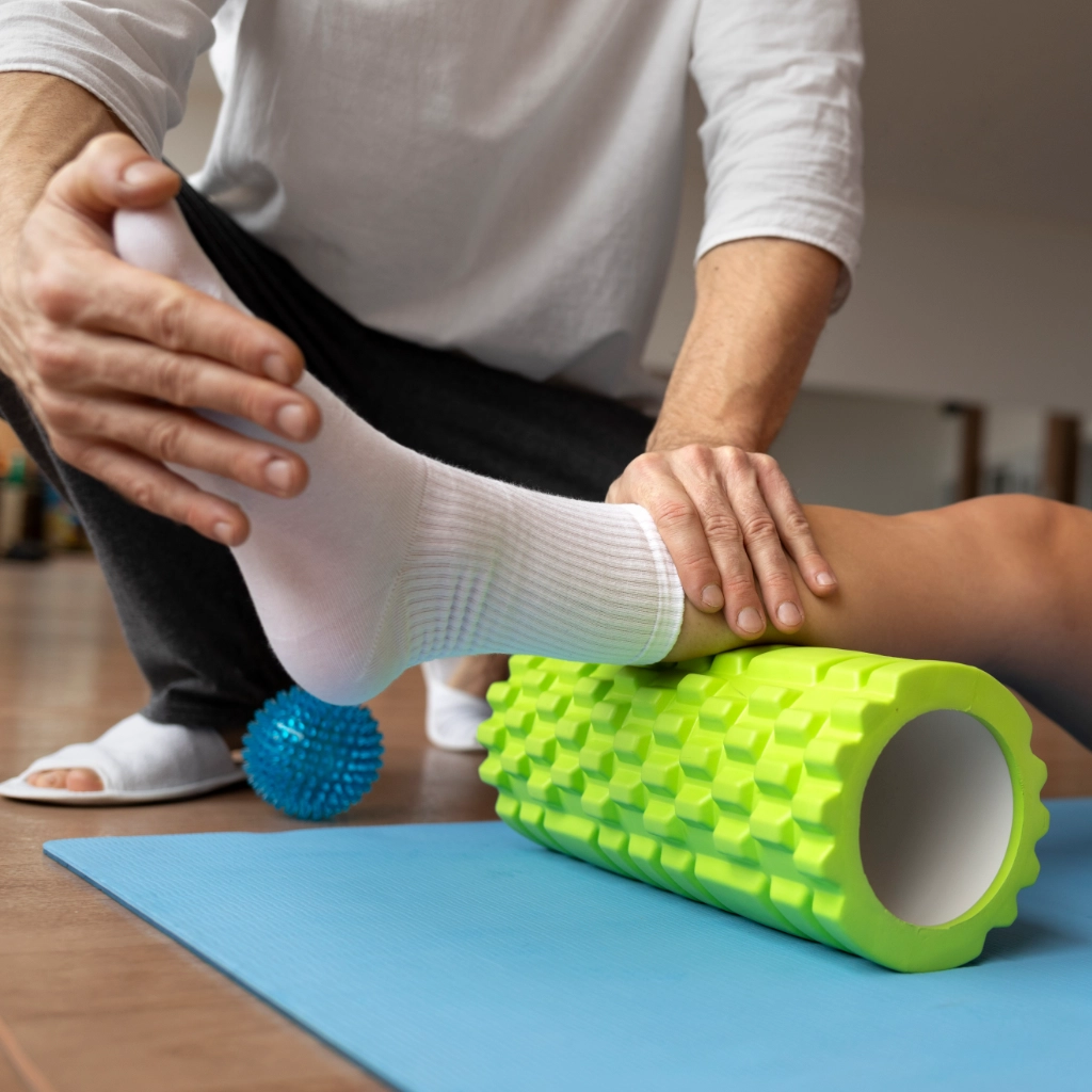 Paciente realizando recuperación muscular con foam roller guiado por fisioterapeuta